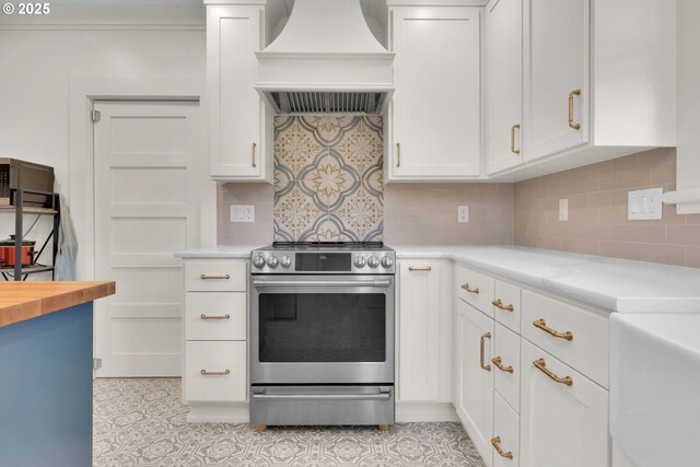 kitchen featuring premium range hood, white cabinets, backsplash, and stainless steel range with electric stovetop