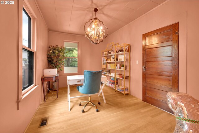 office space with an inviting chandelier, ornamental molding, wood finished floors, and visible vents