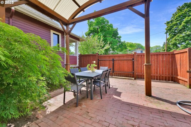 view of patio with a gate, fence, and outdoor dining space