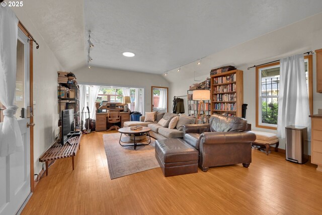 living area featuring rail lighting, vaulted ceiling, and light wood-type flooring