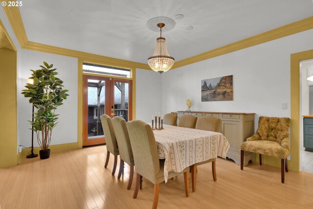 dining room featuring an inviting chandelier, light wood-style floors, french doors, baseboards, and ornamental molding