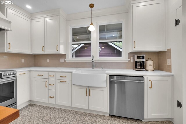 kitchen featuring light countertops, white cabinetry, a sink, appliances with stainless steel finishes, and hanging light fixtures