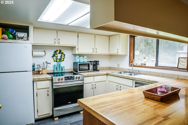 kitchen with tile countertops, dark wood-style flooring, stainless steel appliances, white cabinetry, and a sink