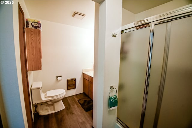 bathroom with visible vents, toilet, vanity, a shower stall, and wood finished floors