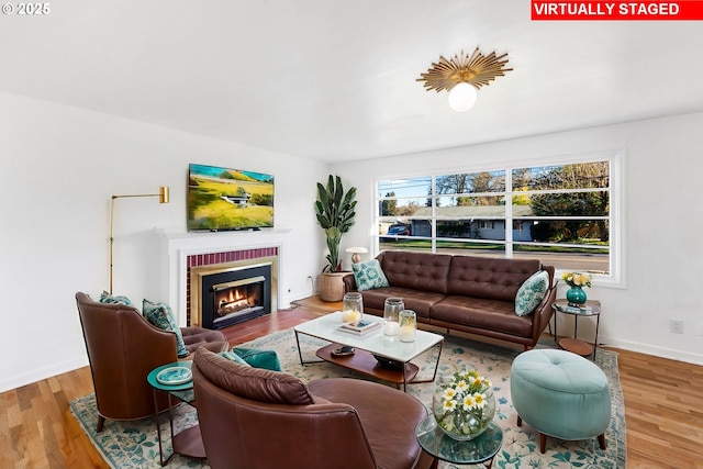 living room with a brick fireplace and hardwood / wood-style floors