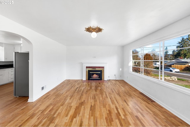 unfurnished living room with a fireplace and light wood-type flooring