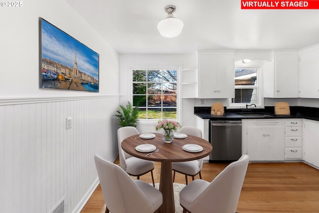 kitchen with sink, stainless steel dishwasher, white cabinetry, and light hardwood / wood-style flooring