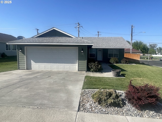ranch-style home featuring an attached garage, concrete driveway, a shingled roof, and a front lawn