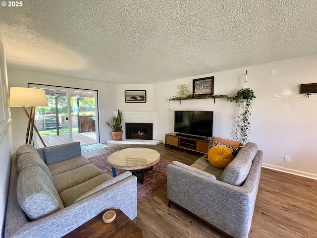 3851 Edgewood Dr, North Bend, OR 97459 - living area with a textured ceiling, wood finished floors, baseboards, and a warm lit fireplace