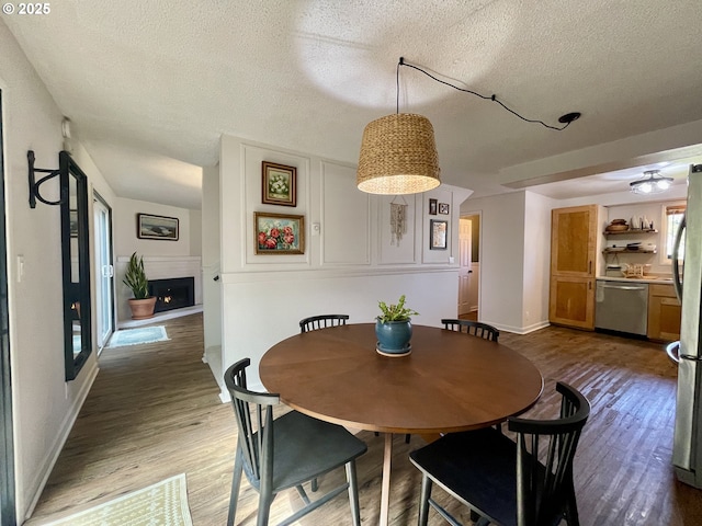 3851 Edgewood Dr, North Bend, OR 97459 - dining space with a textured ceiling, wood finished floors, a lit fireplace, baseboards, and ceiling fan