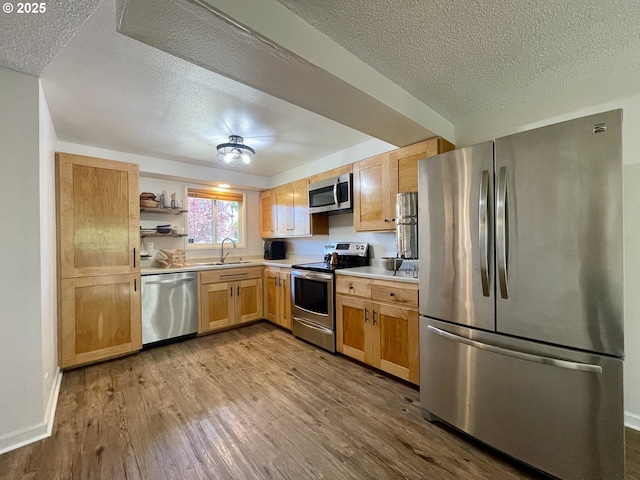 3851 Edgewood Dr, North Bend, OR 97459 - kitchen featuring stainless steel appliances, a textured ceiling, a sink, wood finished floors, and light countertops
