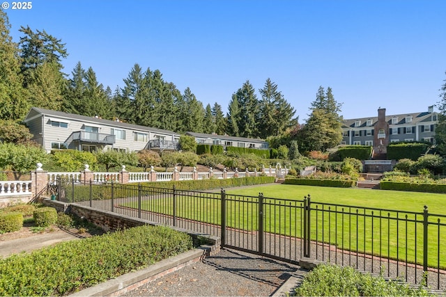 view of community featuring a lawn and fence