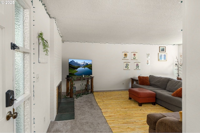 living area featuring a textured ceiling, a brick fireplace, and wood finished floors