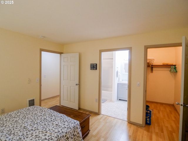5142 SW Multnomah Blvd Unit A, Portland, OR 97219 - bedroom featuring visible vents, a walk in closet, light wood-style flooring, ensuite bathroom, and a closet