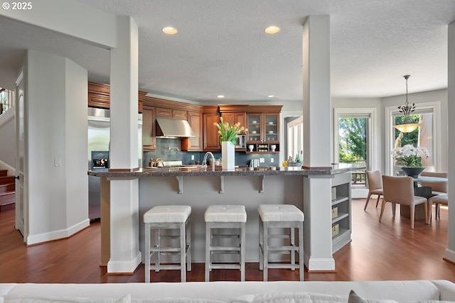 4055 NW Twilight Ter, Portland, OR 97229 - kitchen featuring under cabinet range hood, brown cabinets, dark wood finished floors, a breakfast bar area, and stainless steel refrigerator with ice dispenser