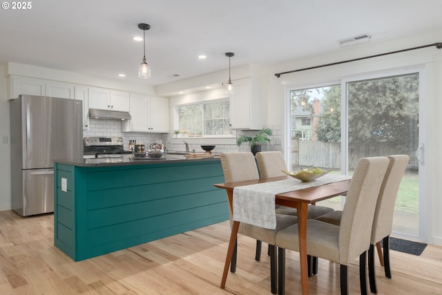 kitchen featuring pendant lighting, white cabinets, backsplash, light hardwood / wood-style floors, and stainless steel appliances