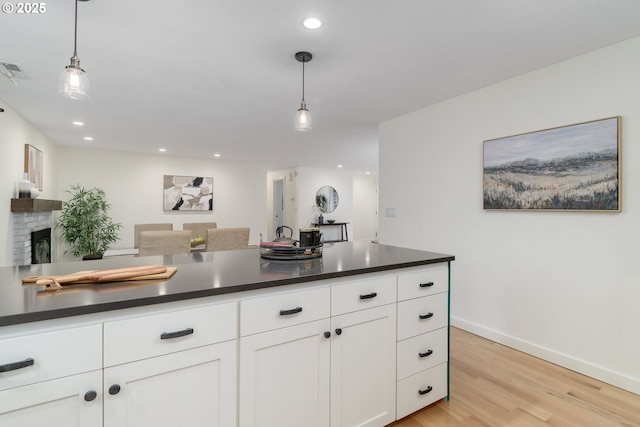 kitchen with hanging light fixtures, white cabinets, and light hardwood / wood-style flooring