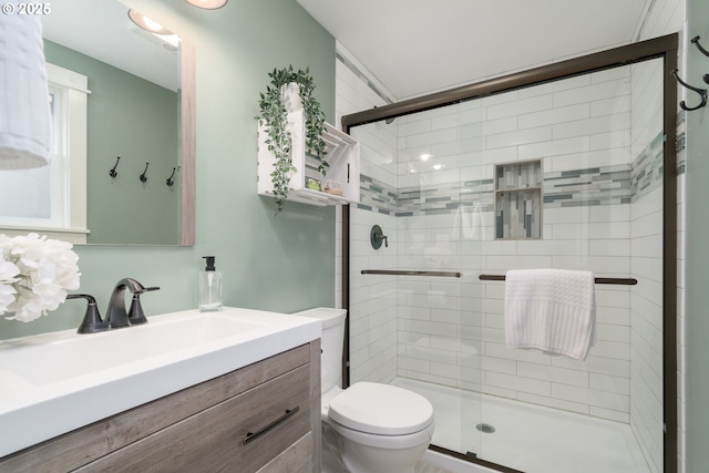 bathroom with a shower with door, vanity, and toilet