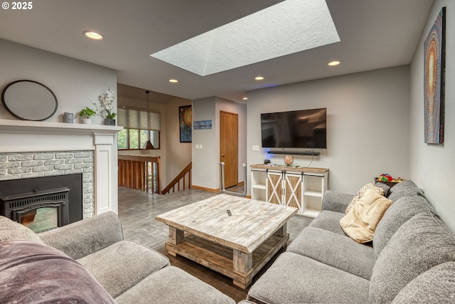 living room featuring a skylight, a fireplace, wood finished floors, baseboards, and recessed lighting