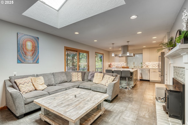 living area featuring a skylight, a brick fireplace, and recessed lighting