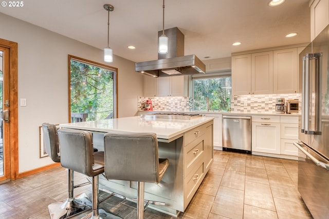 kitchen featuring light countertops, tasteful backsplash, stainless steel appliances, and island exhaust hood