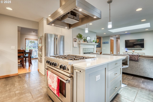 kitchen featuring premium appliances, extractor fan, a stone fireplace, and open floor plan