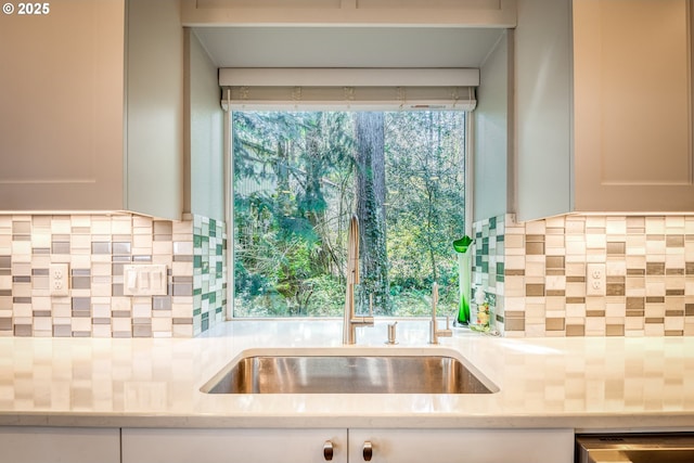 kitchen with white cabinets, a sink, light countertops, backsplash, and dishwashing machine