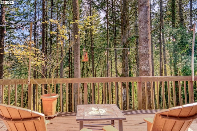 deck featuring outdoor dining space and a wooded view