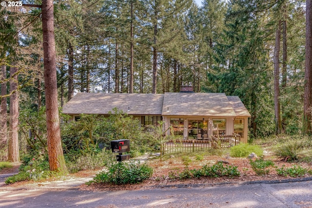view of front of property featuring a shingled roof, covered porch, and a chimney