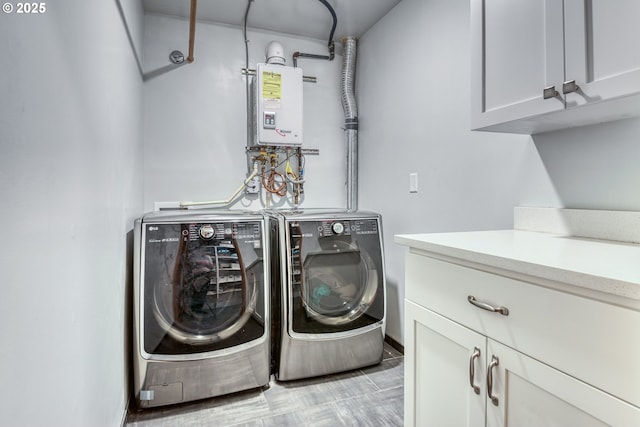 clothes washing area with cabinet space, tankless water heater, and washer and dryer