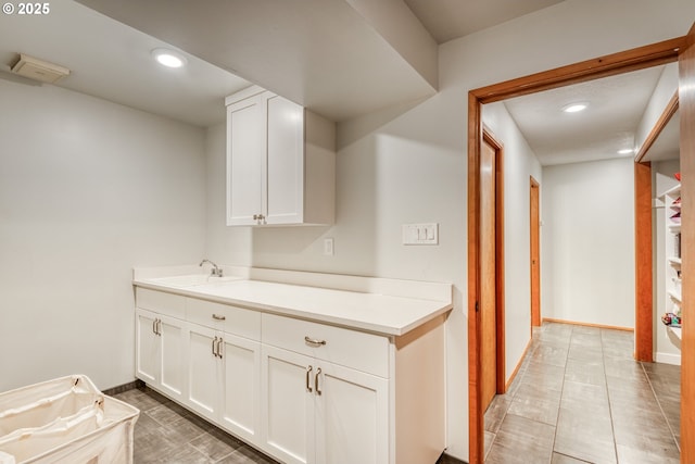 kitchen featuring recessed lighting, a sink, baseboards, and white cabinets