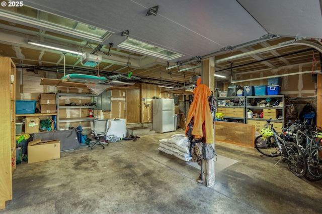 basement with a garage, freestanding refrigerator, and electric panel