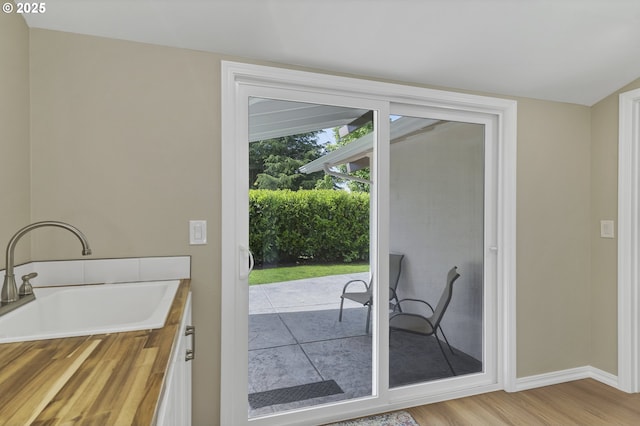 entryway featuring wood finished floors, baseboards, and a sink