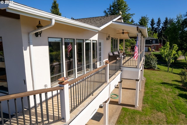 wooden terrace with a ceiling fan and a lawn