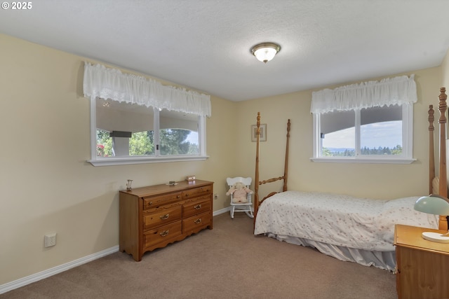 bedroom featuring baseboards, light carpet, and a textured ceiling