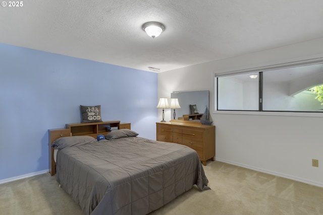 bedroom with light carpet, a textured ceiling, and baseboards