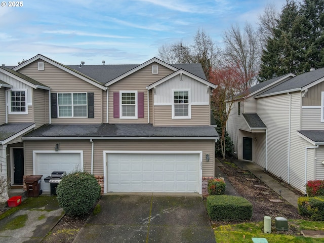 townhome / multi-family property with board and batten siding, brick siding, driveway, and a garage