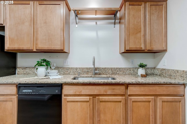 kitchen with light brown cabinetry, dishwasher, a sink, and light stone countertops