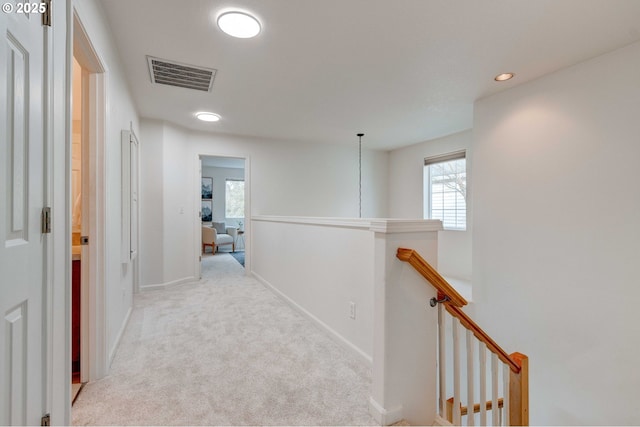 corridor featuring carpet flooring, an upstairs landing, visible vents, and baseboards