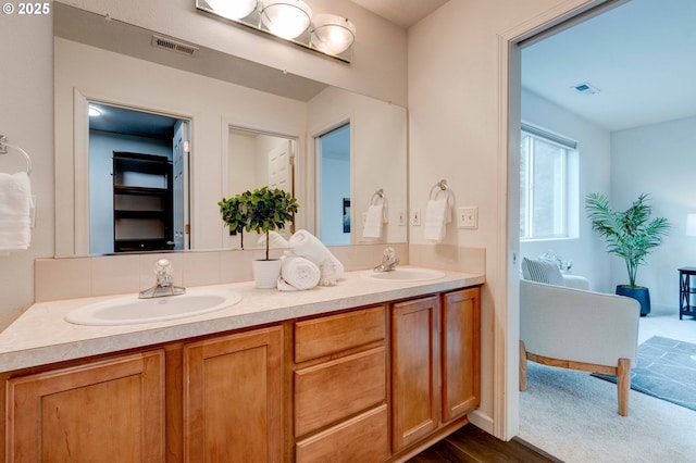 bathroom with visible vents, a sink, and double vanity