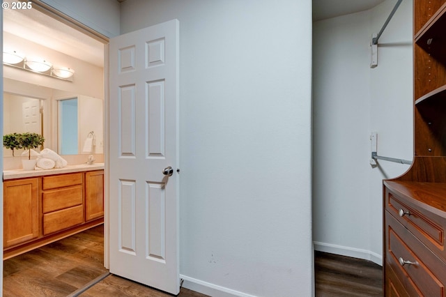 bathroom with double vanity, a sink, baseboards, and wood finished floors