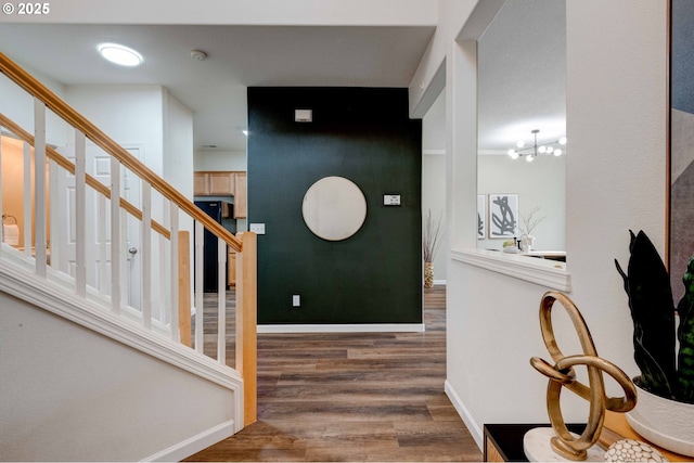 entryway featuring stairs, a notable chandelier, wood finished floors, and baseboards