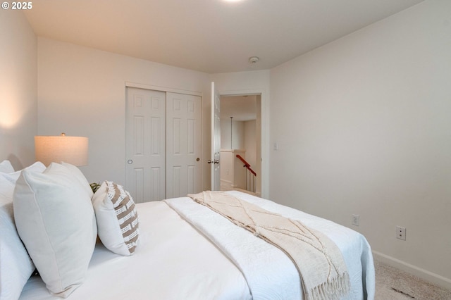 carpeted bedroom featuring baseboards and a closet