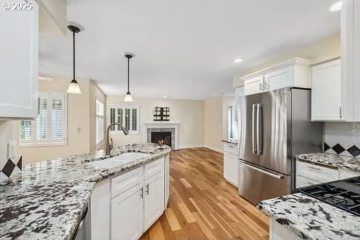 5364 Rosewood St, Lake Oswego, OR 97035 - kitchen with a sink, freestanding refrigerator, white cabinets, a warm lit fireplace, and light wood-type flooring