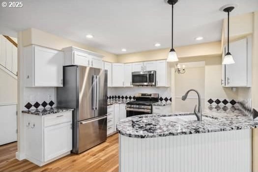 5364 Rosewood St, Lake Oswego, OR 97035 - kitchen with appliances with stainless steel finishes, a peninsula, light wood finished floors, a sink, and light stone countertops