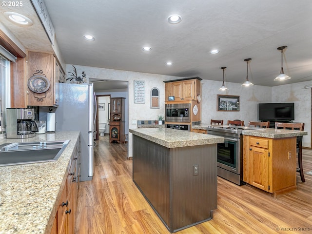 kitchen with light wood finished floors, recessed lighting, stainless steel appliances, hanging light fixtures, and a center island