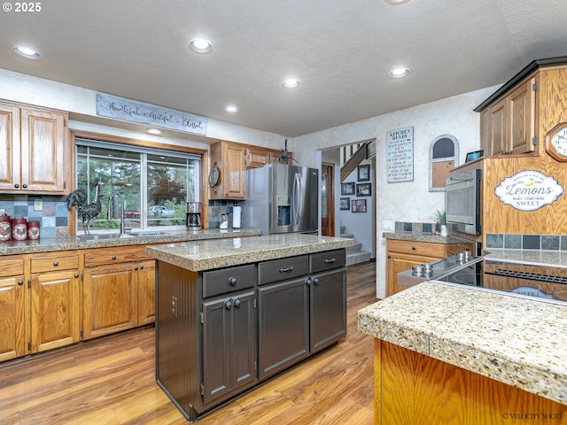 kitchen featuring a center island, light wood-style floors, stainless steel fridge, and a sink