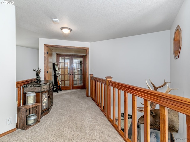 corridor featuring carpet flooring, french doors, baseboards, and a textured ceiling