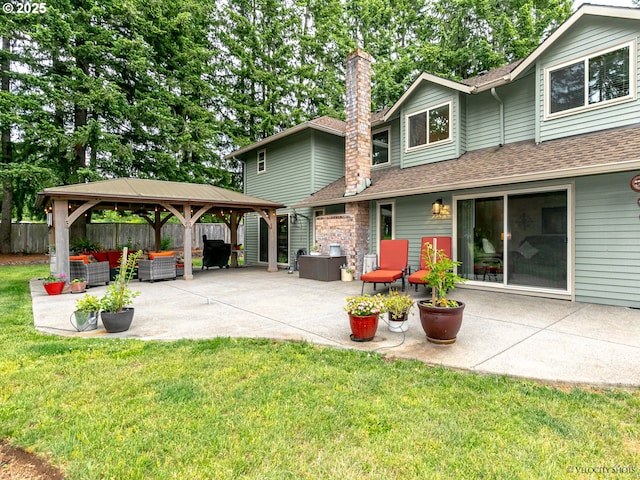 back of house with fence, a chimney, a gazebo, a patio area, and a lawn