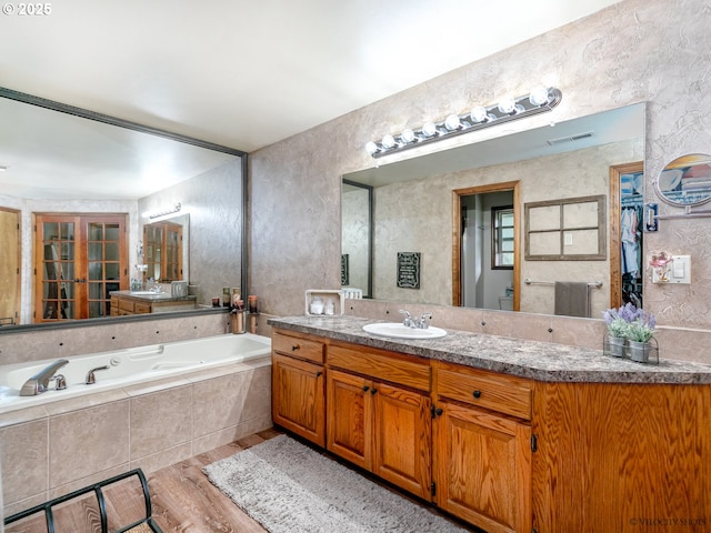 full bathroom featuring visible vents, a garden tub, french doors, wood finished floors, and vanity